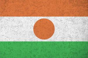 niger-flagge in hellen farben auf alter reliefputzwand dargestellt. strukturierte Fahne auf rauem Hintergrund foto