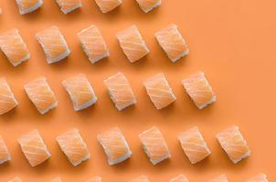 Philadelphia Rolls mit Lachs auf orangefarbenem Hintergrund. Minimalismus Draufsicht flaches Laienmuster mit japanischem Essen foto