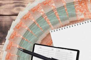 3 kubanische Pesos-Konvertierungsscheinfächer und Notizblock mit Kontaktbuch und schwarzem Stift. Konzept der Finanzplanung und Geschäftsstrategie foto