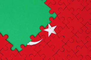 Die türkei-Flagge ist auf einem fertigen Puzzle mit freiem Platz für grüne Kopien auf der linken Seite abgebildet foto