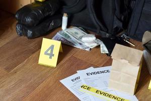 Beweiskette von Verwahrungsetiketten und brauner Papiertüte liegt mit großen Heroinpaketen und Packungen mit Geldscheinen als Beweismittel im Ermittlungsprozess am Tatort foto