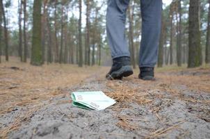 Junger Mann verliert seine Euro-Geldscheine auf russischem Herbsttannenholzpfad. nachlässigkeit und geldverlustkonzept foto