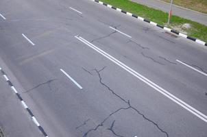 beschädigte schlechte asphaltstraße mit schlaglöchern. Patch-Reparatur von Asphalt foto