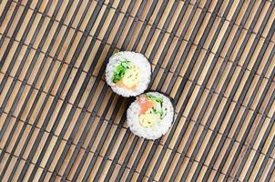 Sushi-Rollen liegen auf einer Nähmatte aus Bambusstroh. traditionelles asiatisches essen. Ansicht von oben. flacher Laienminimalismus mit Kopierraum foto