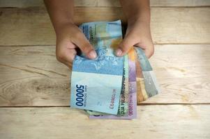 Hand eines jungen Kindes, das indonesisches Geld hält. Rupiah, IDR-Geld. foto