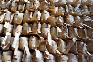 Ketupat ist indonesisches traditionelles Essen. Ketupat ist Reiskuchen, der in einem rautenförmigen Paket aus geflochtenen jungen Kokosnussblättern gekocht wird. foto