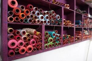 Bunte Fadenspulen, die in der Stoff- und Textilindustrie verwendet werden, mit selektivem Fokus foto