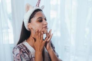 schönes Modell, das kosmetische Cremebehandlung auf ihrem Gesicht anwendet foto