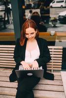 Frau, die am Laptop arbeitet und im Café sitzt und Kaffee trinkt foto