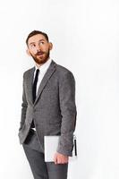 überraschter Mann mit rotem Bart posiert im grauen Anzug mit Tablette in der Hand foto