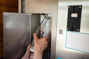 automatischer Kiosk mit Rohmilch vom Bauernhof. Hand hält eine Flasche, in die ein frisches Milchprodukt aus der Maschine gegossen wird. foto