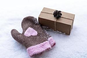 Geschenk in Bastelbox mit Tannenzapfen auf weißem Schnee und Fäustlingen mit rosa Herz, umweltfreundliches Öko-Konzept Frohe Weihnachten und neues Jahr foto