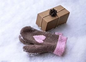 Geschenk in Bastelbox mit Tannenzapfen auf weißem Schnee und Fäustlingen mit rosa Herz, umweltfreundliches Öko-Konzept Frohe Weihnachten und neues Jahr foto