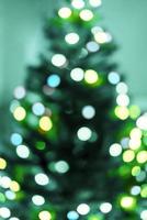 frohe weihnachten hintergrund mit weihnachtsbaum und verschwommenen lichtergirlanden auf ron grün-blauem hintergrund in defokussierung foto