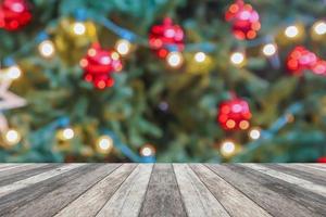 leere hölzerne tischplatte mit unscharfem weihnachtsbaum mit bokeh hellem hintergrund foto