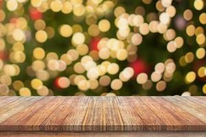 leere hölzerne tischplatte mit unscharfem weihnachtsbaum mit bokeh hellem hintergrund foto