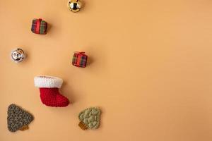 handgefertigter Häkelstrumpf, Geschenk und Weihnachtsbaum auf orangefarbenem Pastellhintergrund. Konzept der frohen Weihnachten und des guten Rutsch ins neue Jahr. foto
