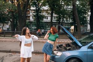 Zwei Frauen mit kaputter Autostraße suchen Hilfe. foto