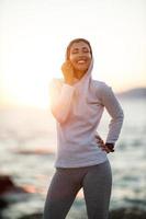 Frau, die den Sommersonnenaufgang genießt und sich vor dem Training am Meer entspannt foto