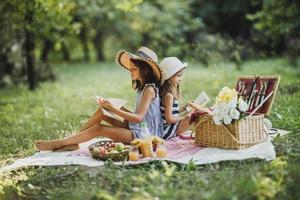 Zwei Schwestern haben Spaß im Park und genießen einen Picknicktag foto