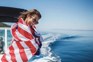 frau, die in die us-nationalflagge gehüllt ist und den tag auf einer privaten yacht verbringt foto