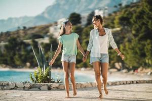 schwestern, die am meer spazieren gehen und die sommerferien genießen foto