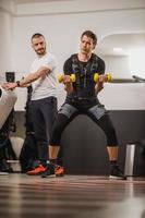 mann, der ems-training mit trainer im fitnessstudio macht foto