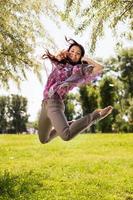glückliche junge Frau, die in den Park springt foto