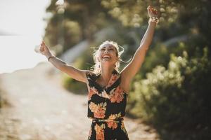 Lächelnde Frau im Blumenkleid hat Spaß am Sommertag foto