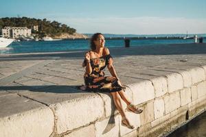 frau, die sommerferien genießt und am meer sitzt foto