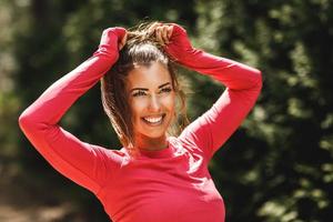 Frau, die sich vor dem Training im Freien die Haare bindet foto