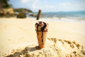 Eistüte auf Sandstrand Hintergrund - schmelzendes Eis am Strand Meer im Sommer heißes Wetter Ozean Landschaft Natur Urlaub im Freien, Eis Schokolade foto