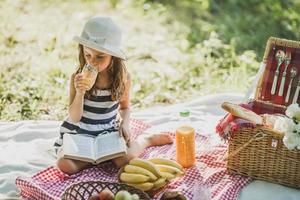 kleines Mädchen, das den Tag in der Natur beim Picknick genießt foto