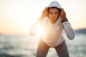 frau, die sommersonnenaufgang genießt und sich während des trainings in der nähe des meeres entspannt foto