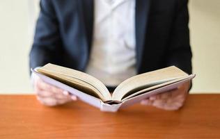 Geschäftsmann oder Student, der ein Buch zur Hand hält - Business Education Study Concept Mann liest Buch auf dem Tisch foto