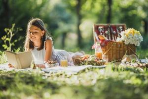 kleines Mädchen, das den Tag in der Natur beim Picknick genießt foto