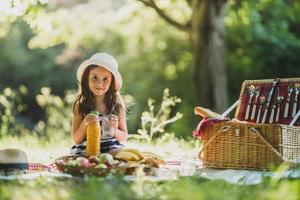 kleines Mädchen, das den Tag in der Natur beim Picknick genießt foto