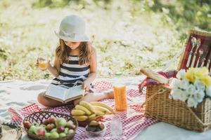 kleines Mädchen, das den Tag in der Natur beim Picknick genießt foto