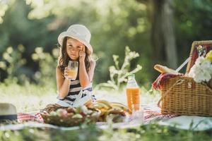 kleines Mädchen, das den Tag in der Natur beim Picknick genießt foto