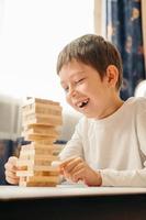 ein lächelnder kaukasischer junge spielt zu hause auf dem tisch in jenga. Gesellschaftsspiele für Kinder und Erwachsene. ein Zeitvertreib ohne Gadgets. Spiele in den Ferien zu Hause. glückliches Kind spielt mit Holzklötzen. foto