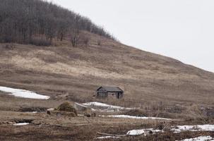 alte verlassene Holzhütte auf dem Hintergrund grüner Hügel. trübes Wetter. graue Wolken foto