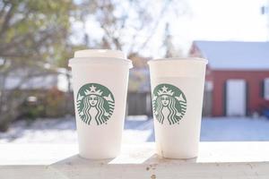 marinette, wi, usa - nov10, 2022- tassen starbucks heißen kaffee auf weißem schnee im wintergarten, frisches und heißes getränk zum mitnehmen konzept.starbucks café café. foto