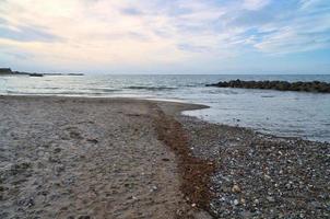 stehen in dänemark mit steindünen. Steine, Muscheln und Algen an der Küste foto