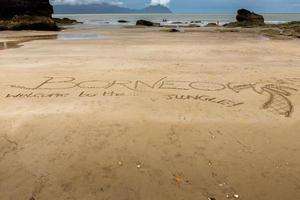 inschrift auf dem sand borneo willkommen im dschungel foto