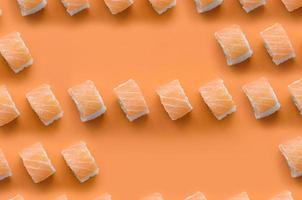 Philadelphia Rolls mit Lachs auf orangefarbenem Hintergrund. Minimalismus Draufsicht flaches Laienmuster mit japanischem Essen foto