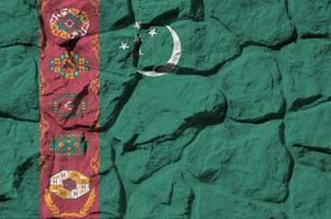 Turkmenistan-Flagge in Lackfarben auf der alten Steinmauer in der Nähe dargestellt. strukturiertes banner auf felswandhintergrund foto