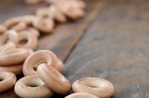 viele frische gelbe bagels liegen auf der oberfläche des alten dunklen holzes. eine beliebte Art von Mehlprodukten. eine der traditionellen russischen Leckereien für Tee foto