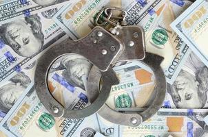 Silberne Polizeihandschellen liegen auf vielen Dollarnoten foto
