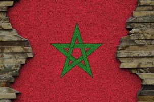 Marokko-Flagge in Lackfarben auf alten Steinmauern in der Nähe dargestellt. strukturiertes banner auf felswandhintergrund foto