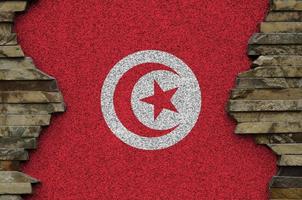 Tunesien-Flagge in Lackfarben auf der alten Steinmauer in der Nähe dargestellt. strukturiertes banner auf felswandhintergrund foto